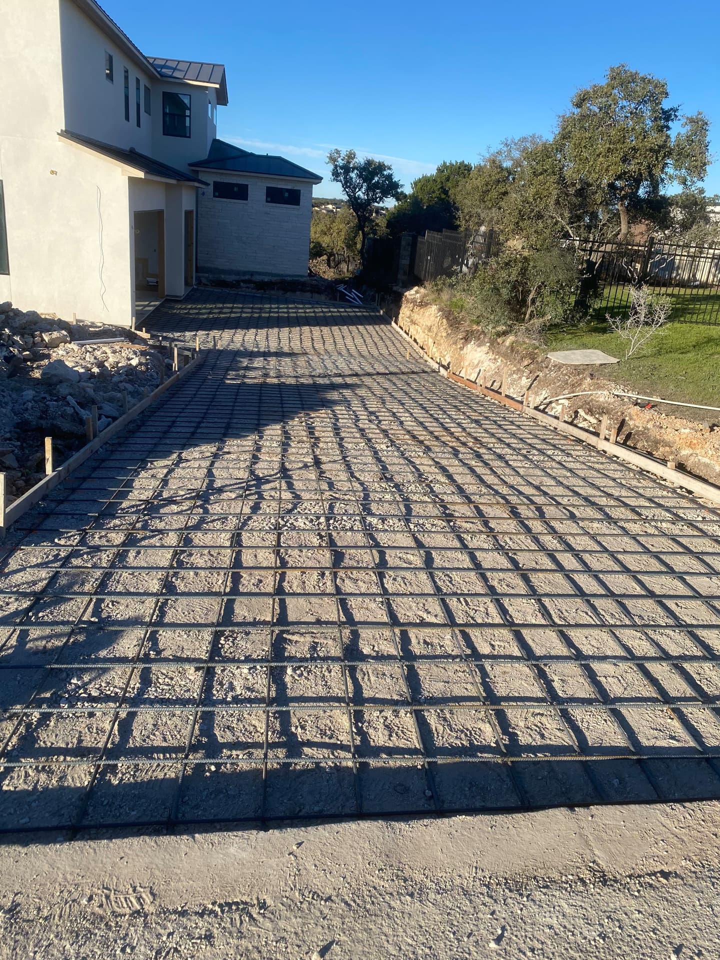 Long residential driveway with rebar grid tied over compacted base before the concrete pour