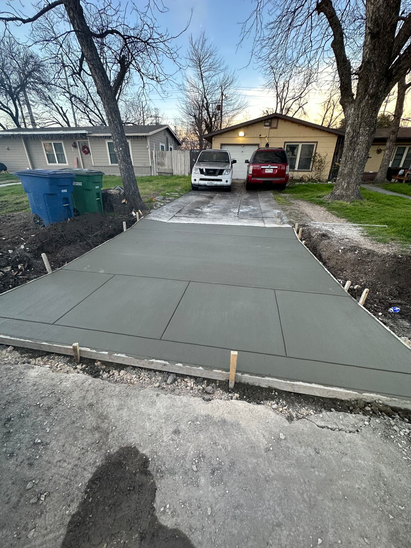 Freshly poured and broom-finished concrete driveway extension still in forms at a San Antonio home