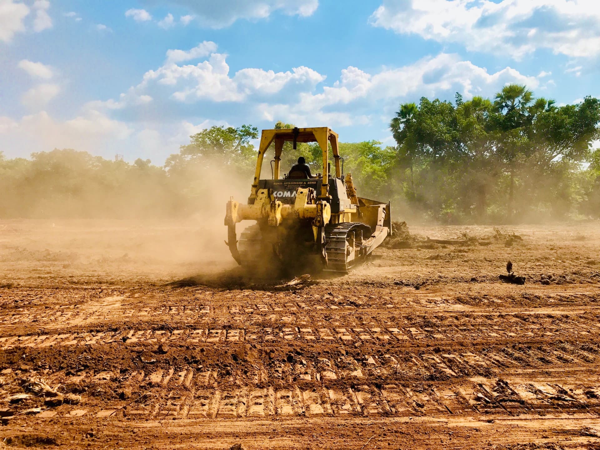 Dozer clearing brush and grading raw dirt on a construction site