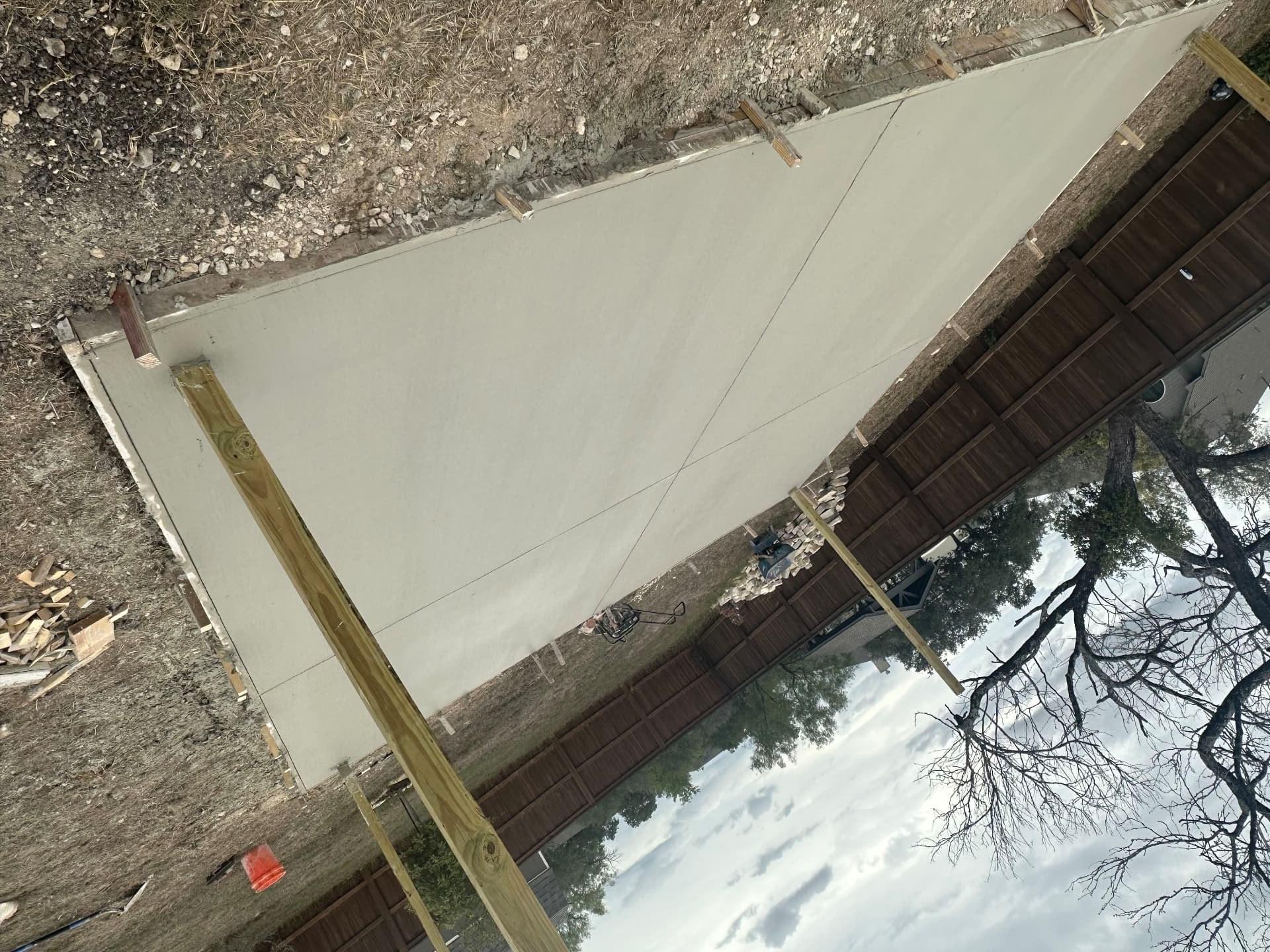 Large finished concrete backyard slab in wood forms along a privacy fence