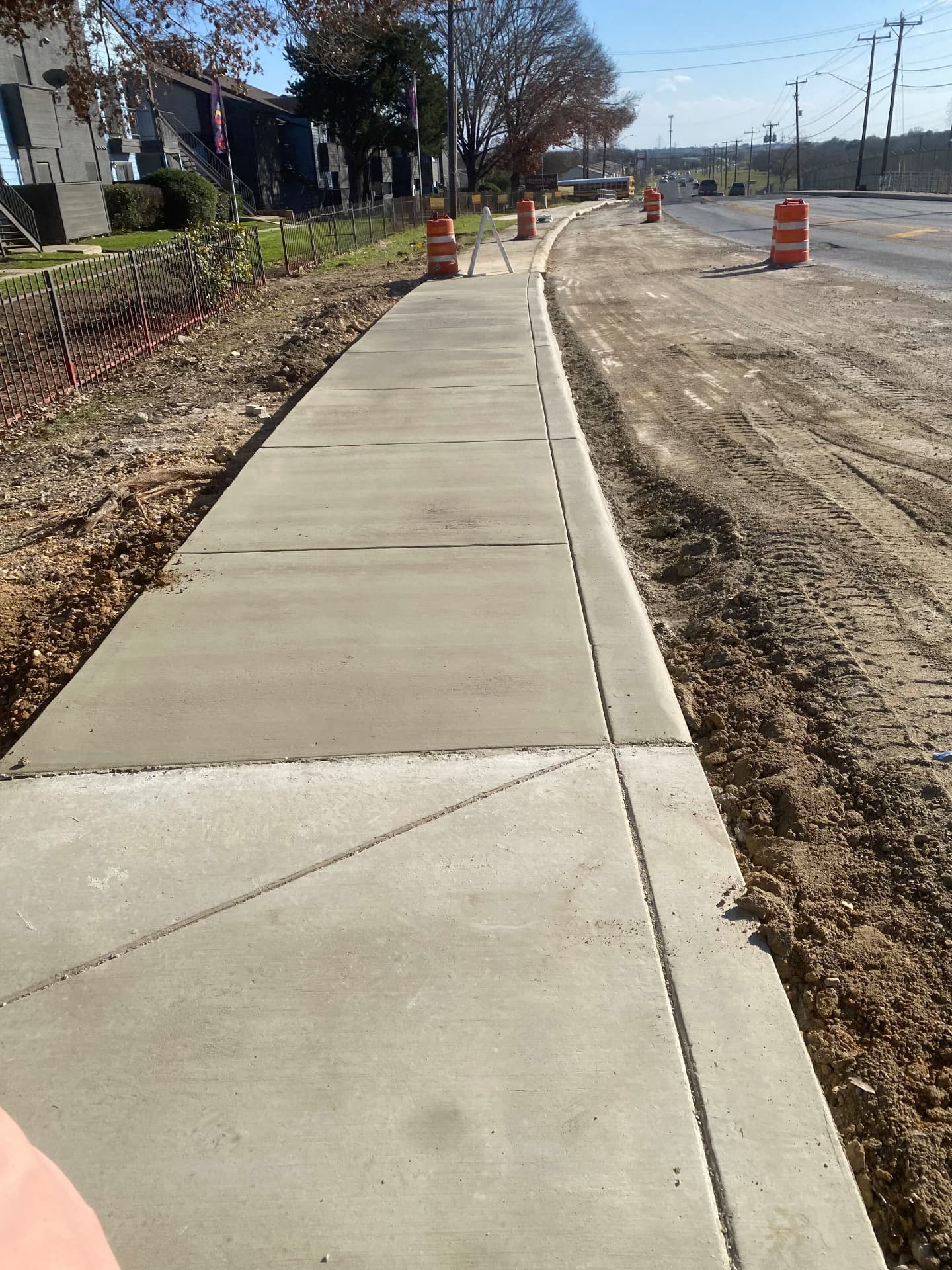 Long new concrete sidewalk and curb section along a road under construction