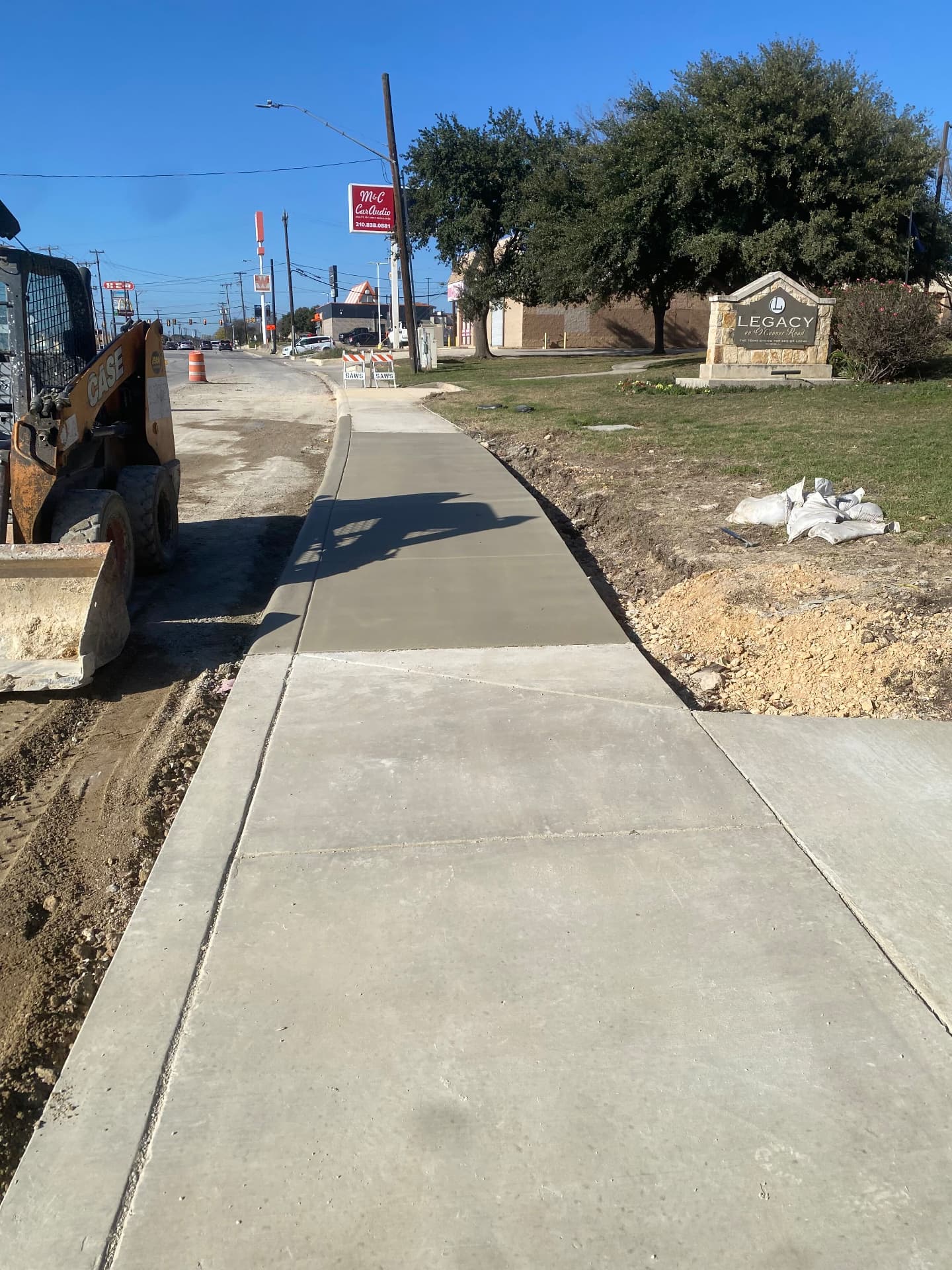 New concrete sidewalk poured along O'Connor Road in front of a commercial property
