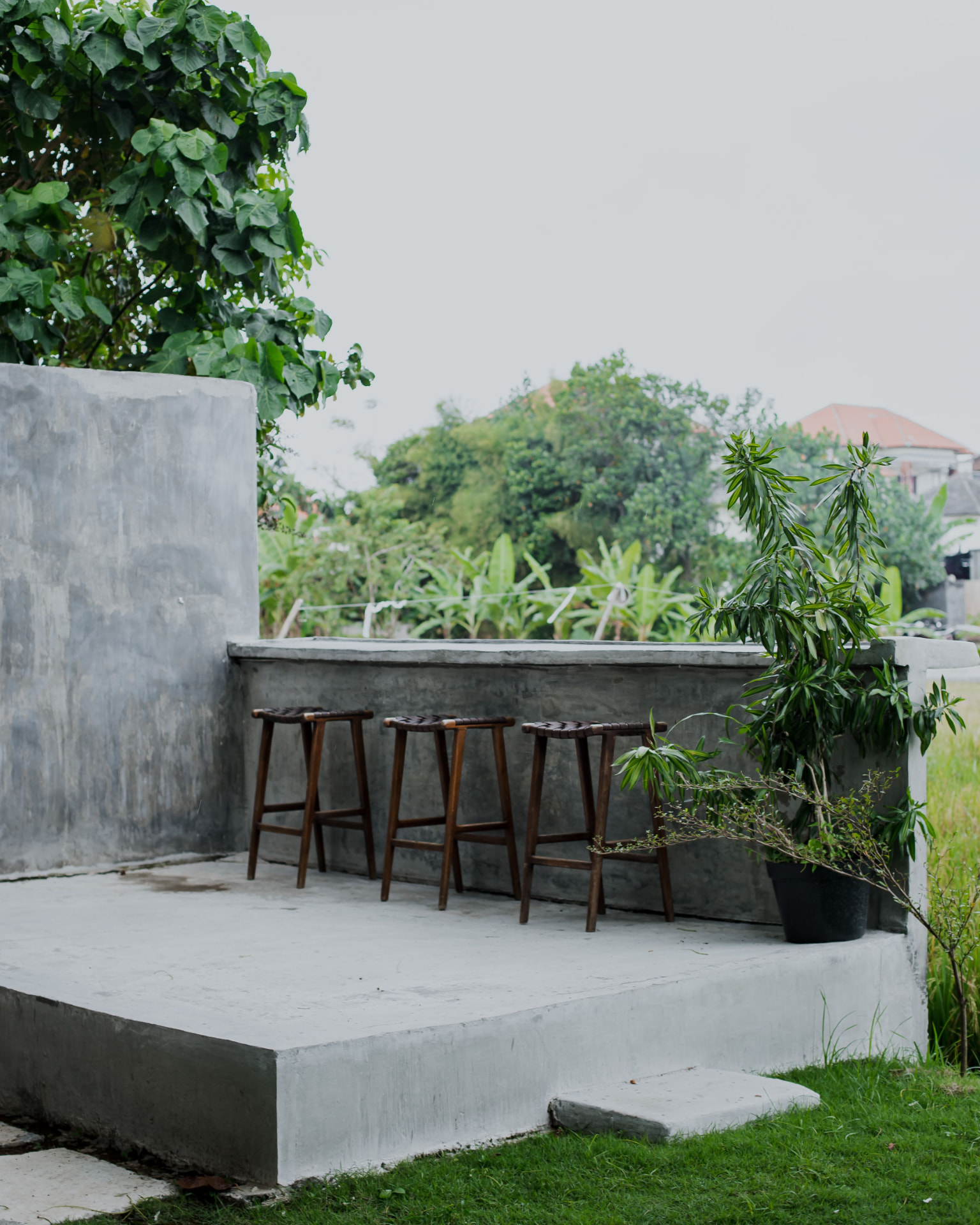 Smooth concrete patio slab with a seating ledge and bar stools in a shaded backyard
