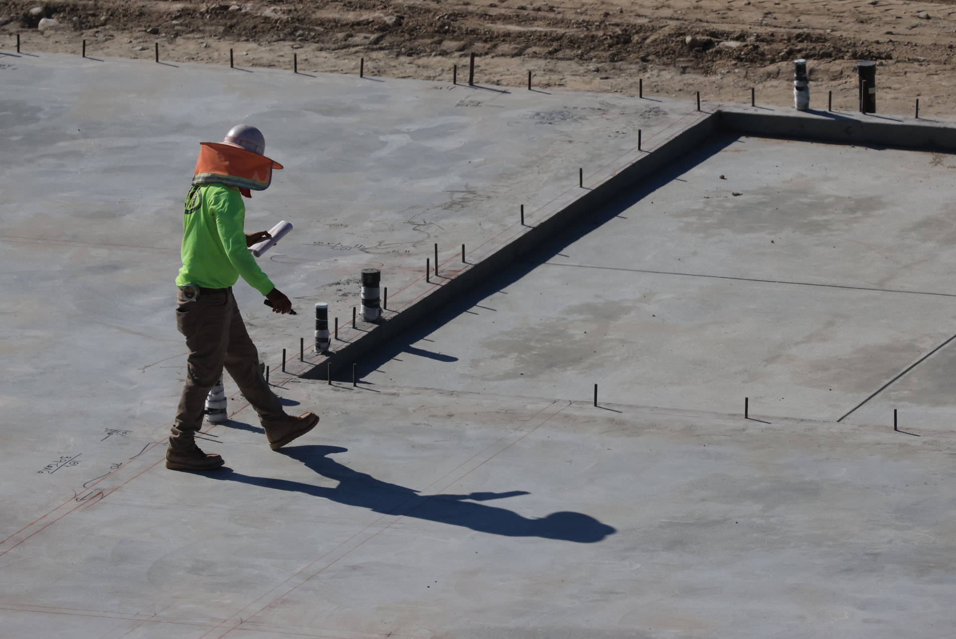 Concrete crew member walking a finished foundation slab with anchor bolts set in San Antonio, TX